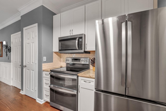 kitchen featuring ornamental molding, backsplash, wood finished floors, white cabinetry, and stainless steel appliances