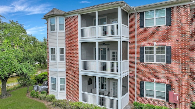 rear view of property featuring cooling unit, a lawn, a sunroom, and a balcony