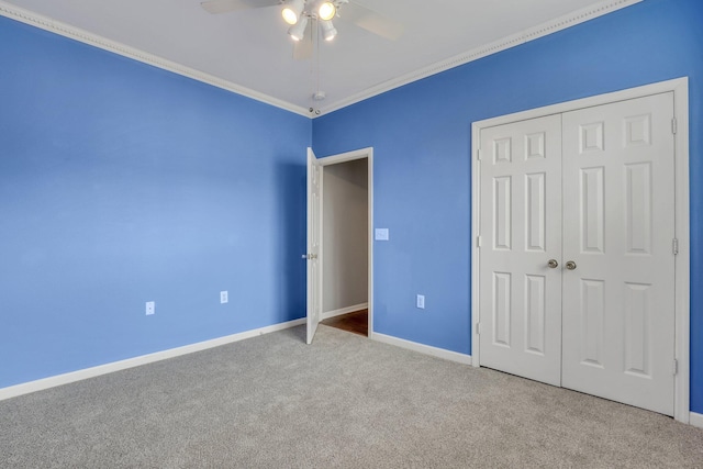 unfurnished bedroom featuring carpet, baseboards, ceiling fan, ornamental molding, and a closet