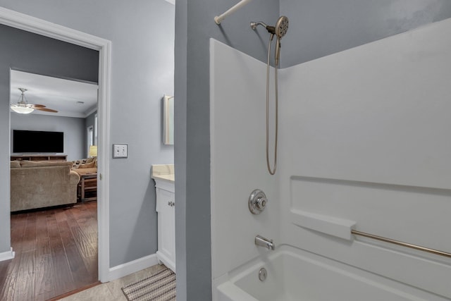 full bathroom featuring vanity, wood finished floors, a ceiling fan, baseboards, and bathtub / shower combination