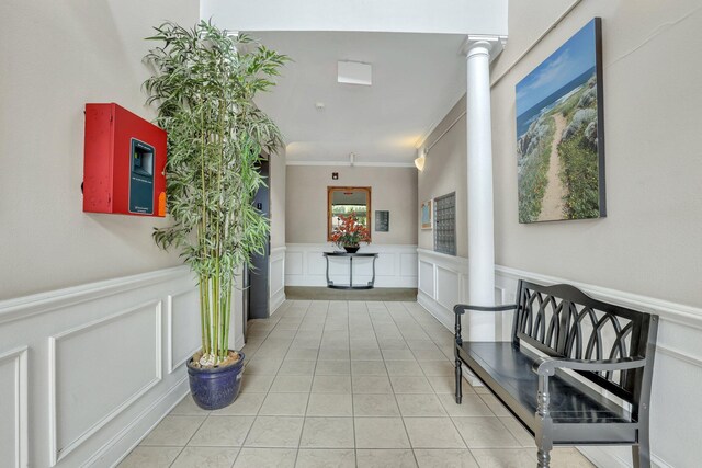 hallway featuring ornamental molding, ornate columns, and light tile patterned floors