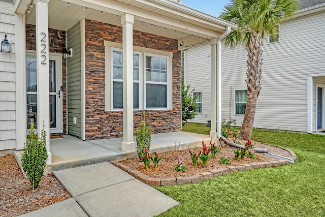 view of exterior entry featuring stone siding and covered porch