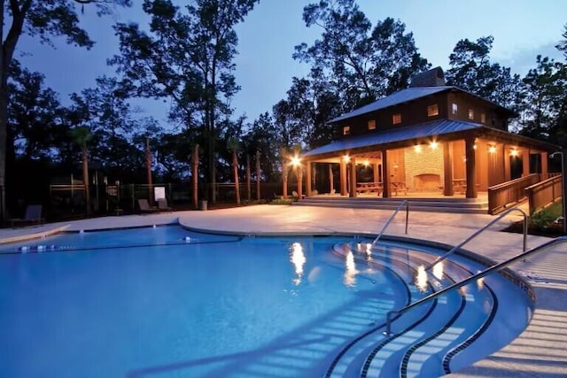 pool at dusk with a patio area