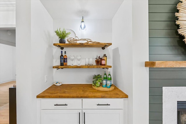 bar featuring hardwood / wood-style floors and white cabinets