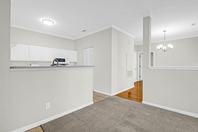 kitchen with white cabinetry, light tile patterned flooring, pendant lighting, a chandelier, and crown molding