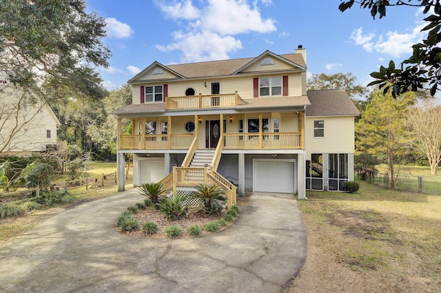 raised beach house with driveway, a chimney, stairway, a porch, and a front lawn