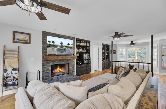 living room with light wood-style floors, a fireplace, and baseboards