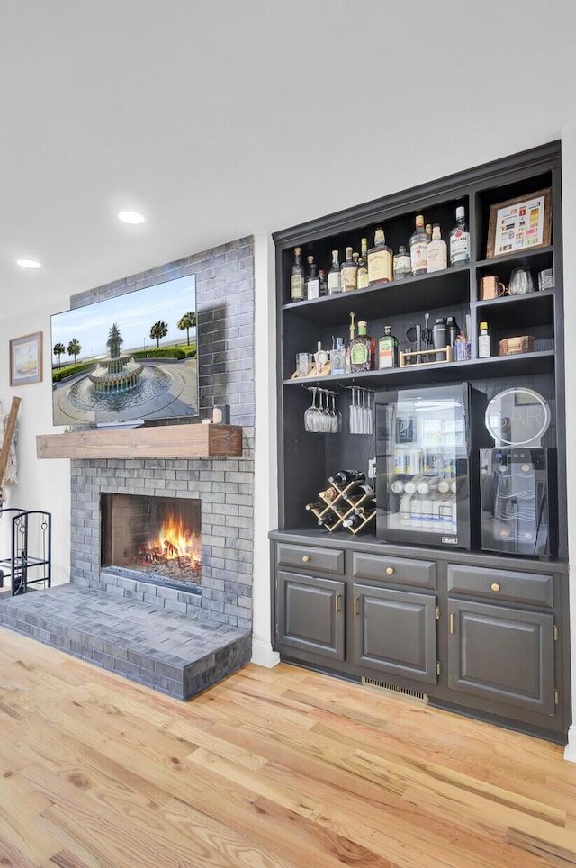 bar featuring a fireplace and light wood-style floors