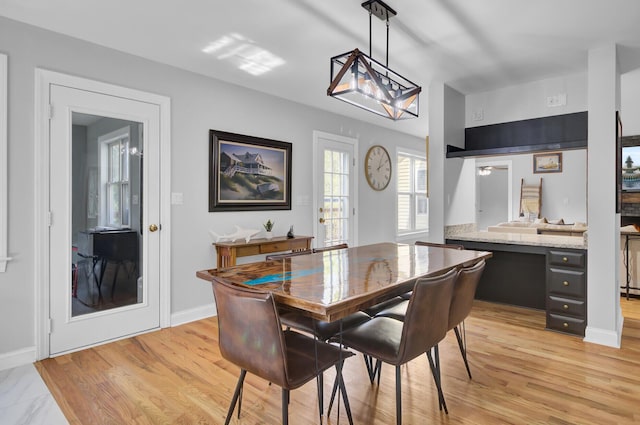 dining space with light wood finished floors and baseboards