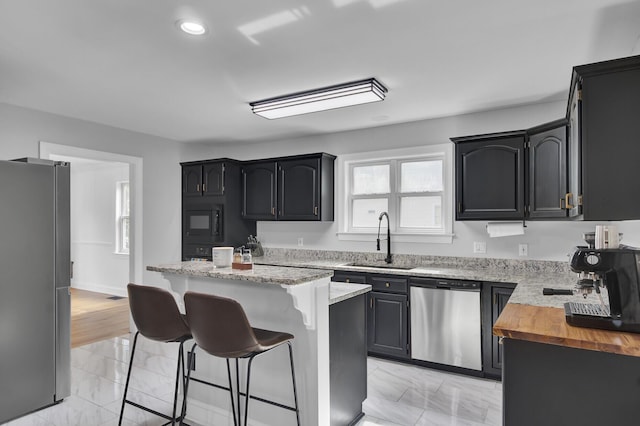 kitchen with marble finish floor, a breakfast bar area, appliances with stainless steel finishes, and a sink