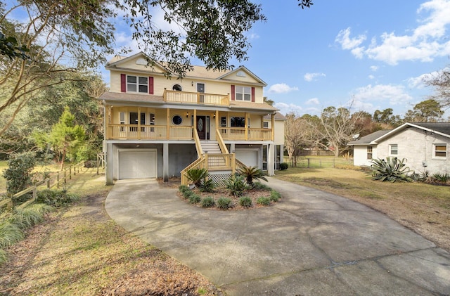 coastal inspired home featuring a porch, concrete driveway, a front yard, a garage, and stairs