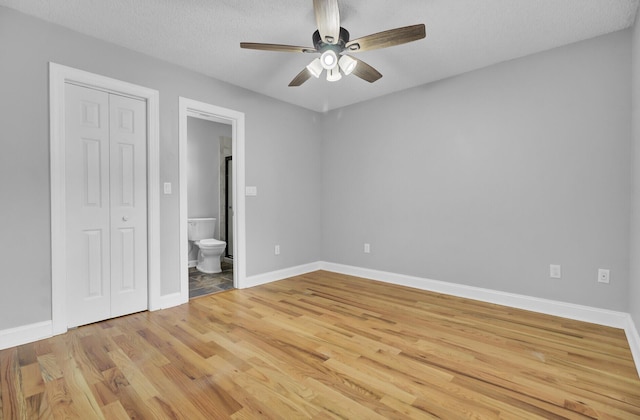 unfurnished bedroom featuring light wood-style floors, a closet, connected bathroom, and baseboards