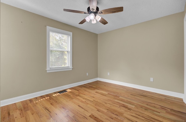 spare room with visible vents, baseboards, a ceiling fan, light wood-style flooring, and a textured ceiling