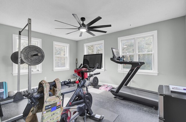 exercise area featuring ceiling fan, baseboards, and a textured ceiling