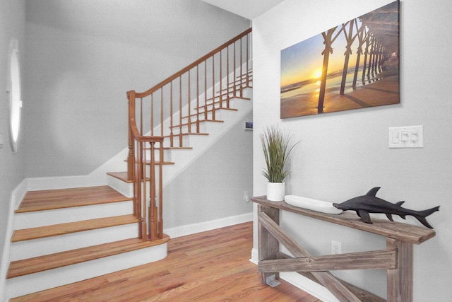 staircase featuring baseboards and wood finished floors