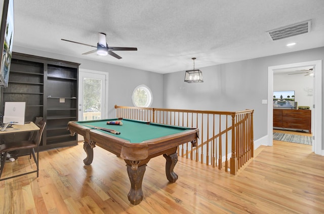 rec room with light wood-type flooring, ceiling fan, visible vents, and a textured ceiling