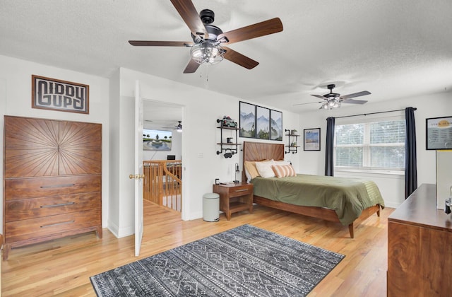 bedroom with light wood-style floors, ceiling fan, and a textured ceiling