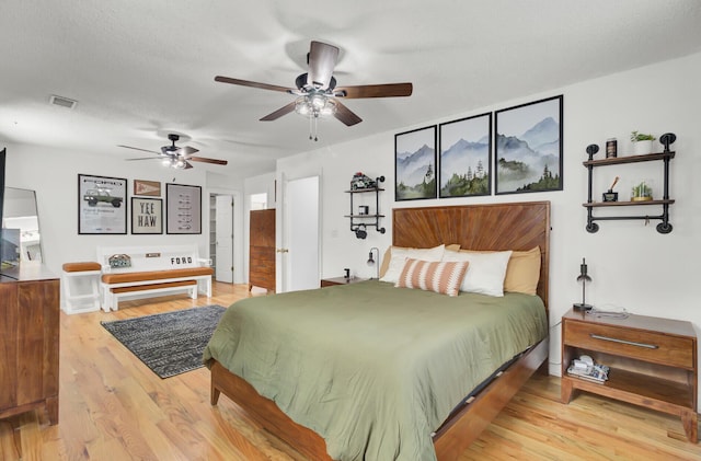 bedroom featuring ceiling fan, a textured ceiling, visible vents, and wood finished floors