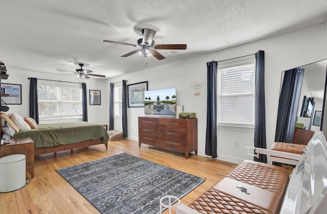 bedroom with light wood-style floors, ceiling fan, baseboards, and a textured ceiling