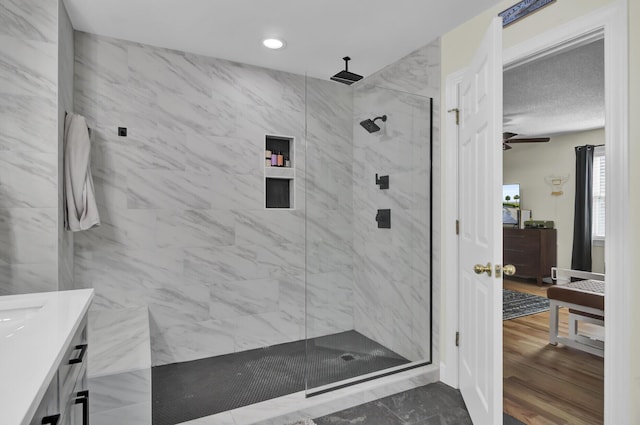 bathroom featuring wood finished floors, a marble finish shower, vanity, and recessed lighting