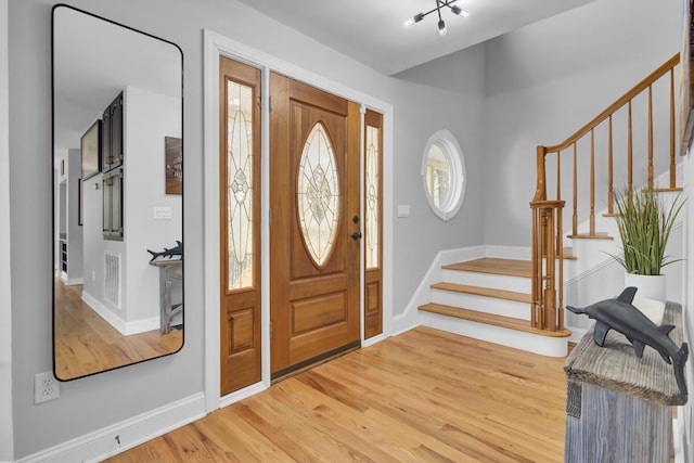 entrance foyer with plenty of natural light, light wood-style flooring, baseboards, and stairs