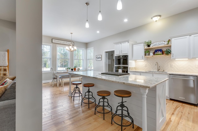 kitchen with dishwasher, hanging light fixtures, a kitchen breakfast bar, a center island, and white cabinets