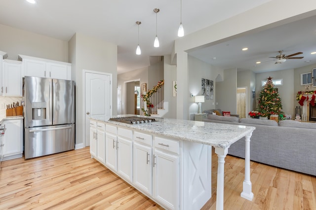 kitchen featuring light wood-type flooring, a kitchen breakfast bar, a kitchen island, stainless steel appliances, and white cabinets