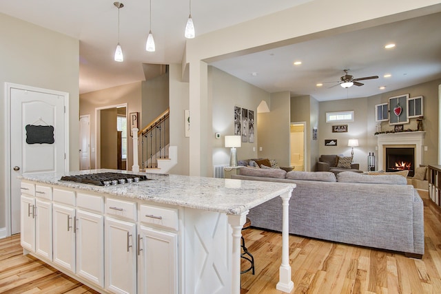 1129 Plantation Overlook Dr, Moncks Corner, SC 29461 - kitchen featuring stainless steel gas cooktop, ceiling fan, light wood-style flooring, white cabinets, and pendant lighting