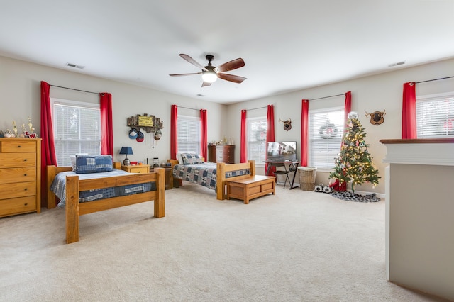 carpeted bedroom featuring multiple windows and ceiling fan