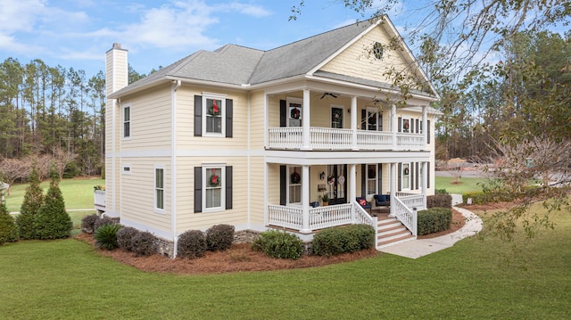 view of front of property with ceiling fan, a balcony, a front yard, and covered porch