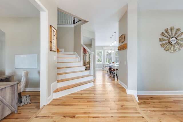 staircase with hardwood / wood-style floors and a chandelier