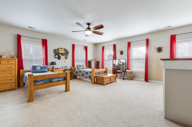 carpeted bedroom featuring ceiling fan and multiple windows