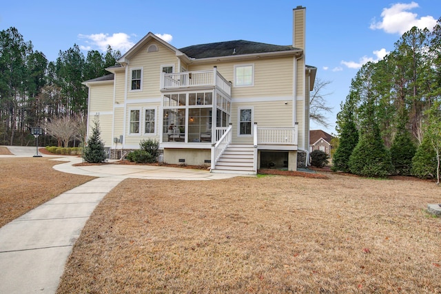 rear view of property with a balcony, a sunroom, and a lawn