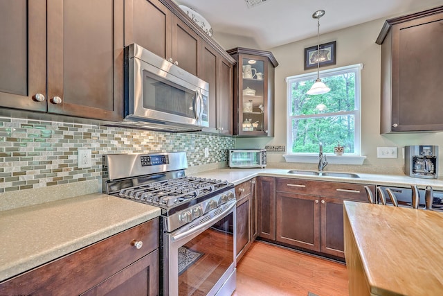 100 Canal Rd, Saint George, SC 29477 - kitchen with appliances with stainless steel finishes, a sink, hanging light fixtures, decorative backsplash, and light wood finished floors