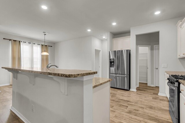 9998 Winged Elm St, Ladson, SC 29456 - kitchen with stainless steel appliances, a breakfast bar area, white cabinetry, light stone counters, and recessed lighting
