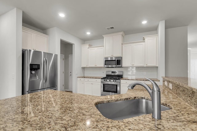 9998 Winged Elm St, Ladson, SC 29456 - kitchen with appliances with stainless steel finishes, a sink, light stone counters, white cabinetry, and recessed lighting