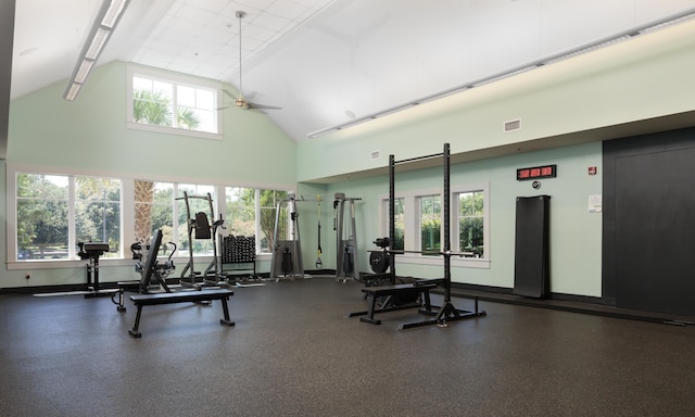 gym with ceiling fan, elevator, plenty of natural light, and high vaulted ceiling