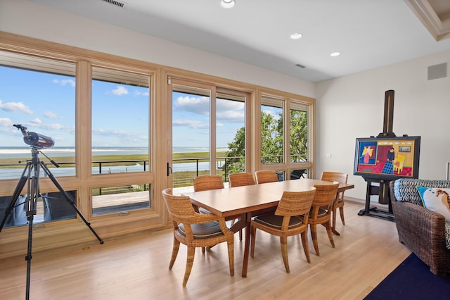 dining room featuring light hardwood / wood-style floors and a water view