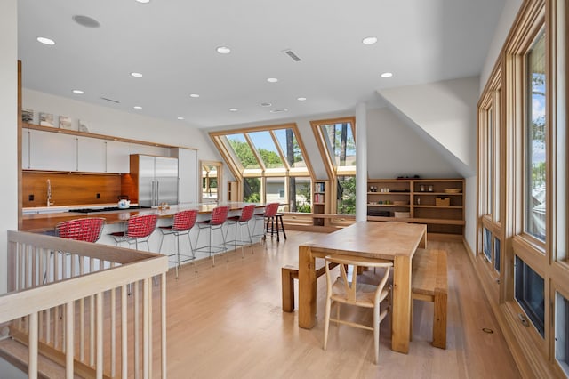 dining space with sink, light hardwood / wood-style flooring, and a skylight