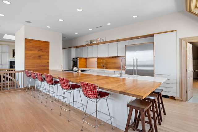 kitchen featuring backsplash, kitchen peninsula, a kitchen bar, white cabinetry, and appliances with stainless steel finishes