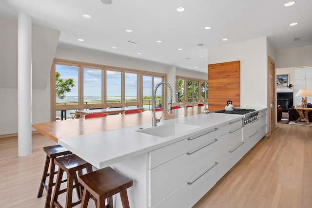 kitchen featuring white cabinetry, a kitchen bar, a large island, stainless steel gas cooktop, and sink