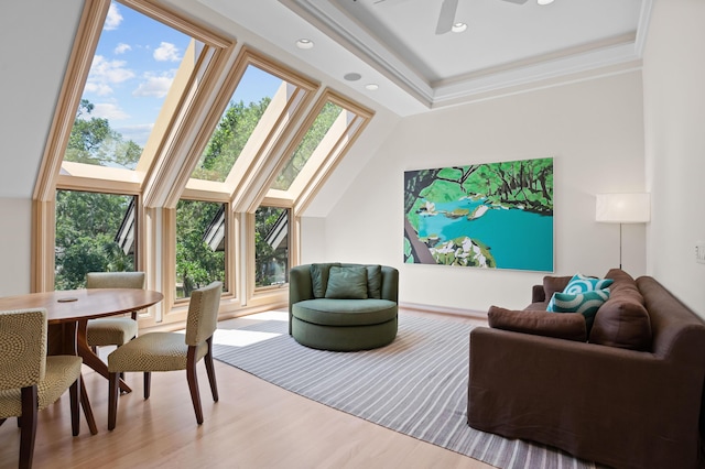 living room with light wood-type flooring, ceiling fan, crown molding, and a high ceiling