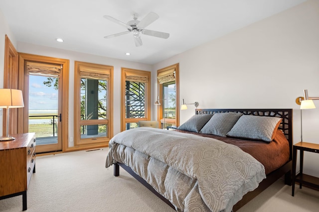 bedroom with ceiling fan, light colored carpet, and multiple windows