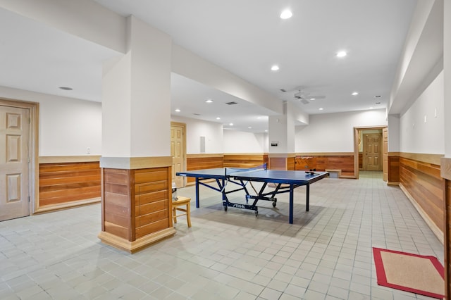 rec room with ceiling fan, light tile patterned floors, and wood walls