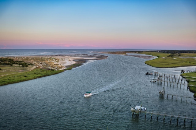 aerial view at dusk with a water view and a view of the beach