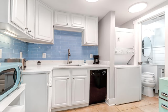 washroom featuring light tile patterned floors, a sink, and stacked washer / drying machine