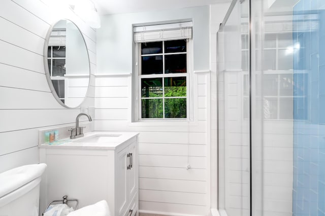 full bath featuring wooden walls, a shower stall, toilet, and vanity