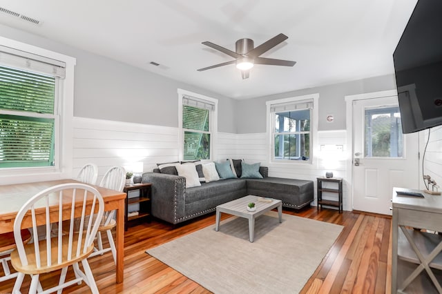 living area with a wainscoted wall, visible vents, and hardwood / wood-style flooring