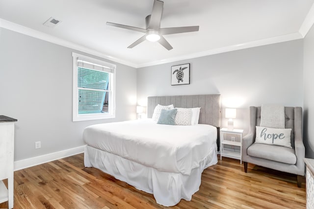 bedroom featuring ornamental molding, wood finished floors, visible vents, and baseboards