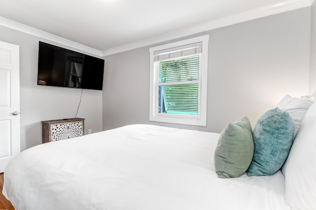 bedroom with wood finished floors and crown molding